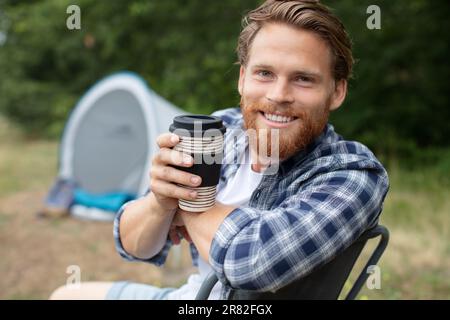 man is enjoying cup of coffee outside the tent Stock Photo