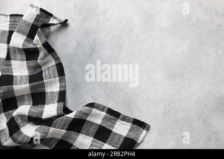 Black checkered tablecloth on light gray textured table, top view. Space for text Stock Photo