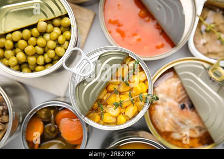 Open tin cans with different products on table, flat lay Stock Photo