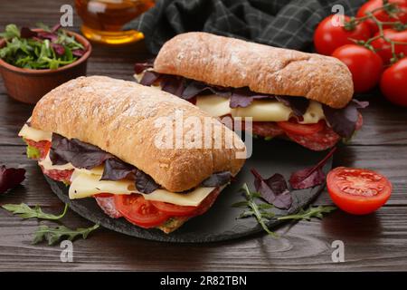 Delicious sandwiches with cheese, salami, tomato on wooden table Stock Photo