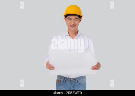 Portrait young asian man is engineer wearing helmet holding and looking blueprint with confident isolated on white background, handsome male is archit Stock Photo