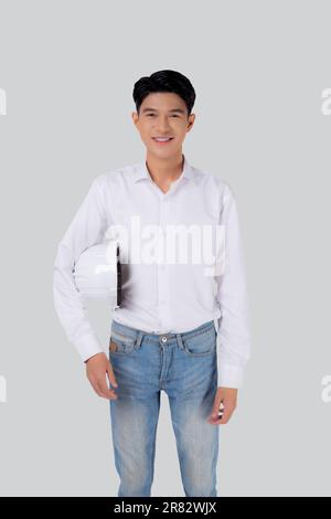 Portrait young asian man is engineer holding helmet standing and smiling with confident isolated on white background, handsome male is architect or co Stock Photo