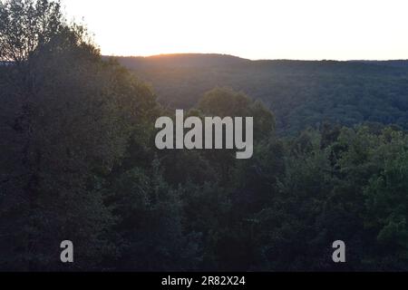 Forested Arkansas mountains with the sun beginning to set behind them. Stock Photo