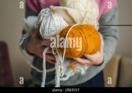 Woman holding colored skeins of wool yarn in her hands. Creative concept of knitting. Goods for knitting, needlework. Stock Photo
