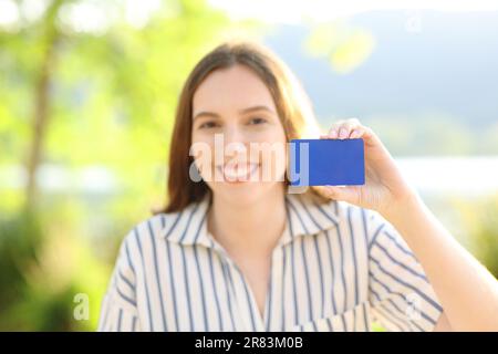 Happy woman showing credit card at camera in nature Stock Photo