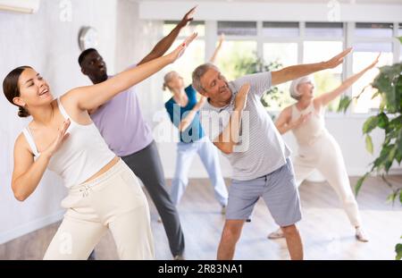 Female instructor teaches mature students of dance class basic movements of hip hop dance Stock Photo