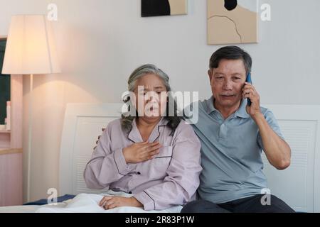 Senior man calling doctor to tell about wife suffering from heartache Stock Photo