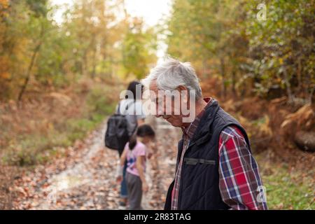 Grandfather with his grandson and granddaughter in the autumn forest, family hiking Stock Photo