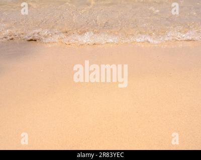 Clean empty beach background, movement of clear sea water and wave surf on sandy beach ocean, seashore, coastline, close-up. Top view beach with copy Stock Photo