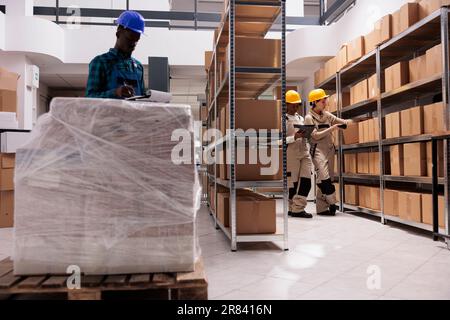 Delivery service storage workers managing parcel receiving and scanning boxes. Caucasian and african american warehouse colleagues using barcode scanner and checking freight documents before shipping Stock Photo