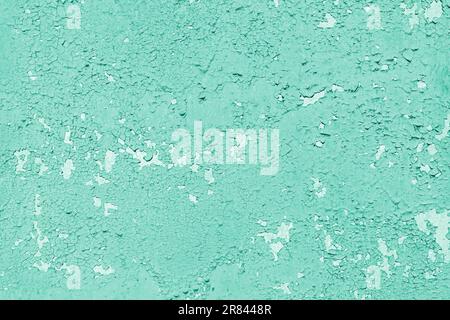 Goncrete wall with old cracked, peeling flaking turquoise paint. Weathered rough painted surface with patterns of cracks and peeling, grunge, aged tex Stock Photo