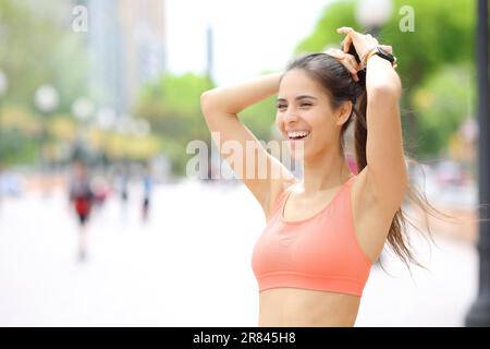 Happy runner making ponnytail laughing in the street Stock Photo