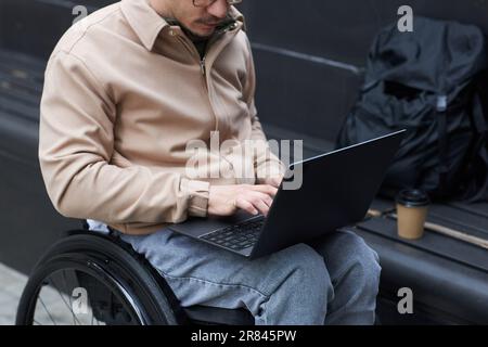 Close-up of young man with disability working online on laptop outdoors Stock Photo