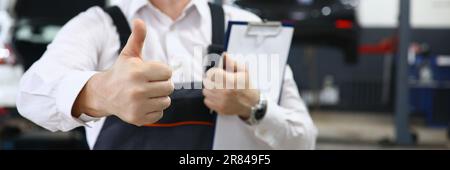 Portrait of male mechanic showing thumbs up in car service Stock Photo