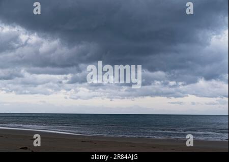 Dark grey clouds gather over the ocean bringing the threat of rain with them. Stock Photo