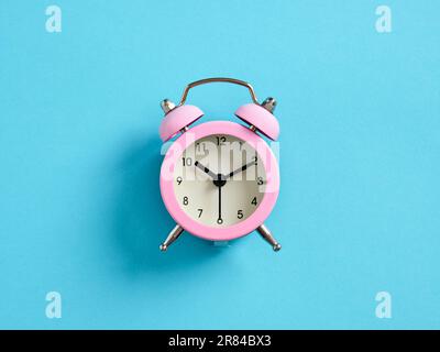 Pink alarm clock on blue background. Time management concept. Stock Photo