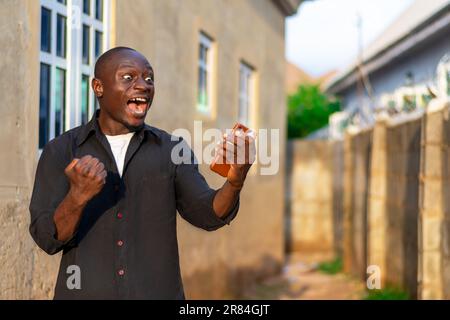 african black man very happy and excited over success he saw on his mobile phone Stock Photo