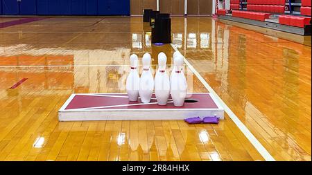 Cornhole, bowling, frisbee, can jam, games set up on a gym floor for high school gym classes. Stock Photo