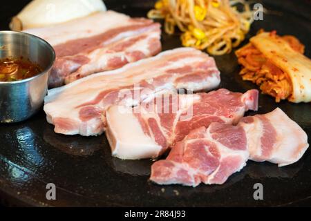 Pan-fried black pork meal in Jeju Korean restaurant, fresh delicious korean food cuisine on iron plate with lettuce, kimchi, banchan and sauce, lifest Stock Photo