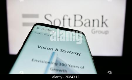 Smartphone with webpage of Japanese investment company SoftBank Group Corp. on screen in front of logo. Focus on top-left of phone display. Stock Photo