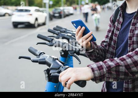 Close up of man hand using mobile app for rental electric scooter. Stock Photo
