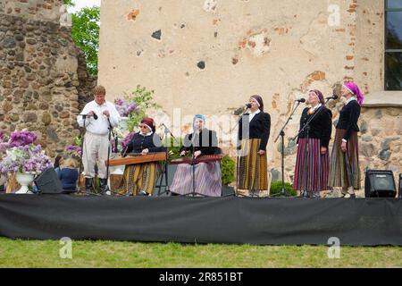 Dobele, Latvia - May 27, 2023. Performance of the folklore group at the historical walls of Dobele castle ruins. People in ethnic colorful national co Stock Photo