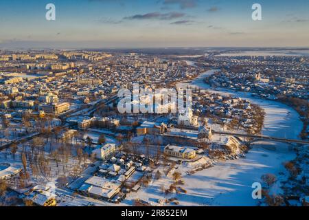 Nice top view of the winter city. Houses and buildings in the snow. Bridge over river. Orthodox churches and a Catholic cathedral. The river is covere Stock Photo