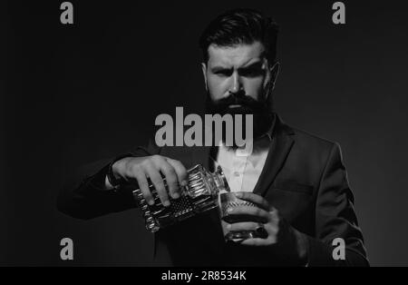 Bartender leather apron holding whisky cocktail in glass. Bearded and glass of whiskey. Stock Photo
