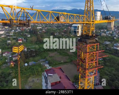 Close-up view from a drone of a construction crane cabin against the backdrop of beautiful mountains. Construction concept Stock Photo