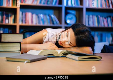 Young woman napping on table in library for education Stock Photo
