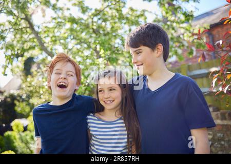 Family Shot With Loving Brothers And Sister In Garden At Home Together Stock Photo