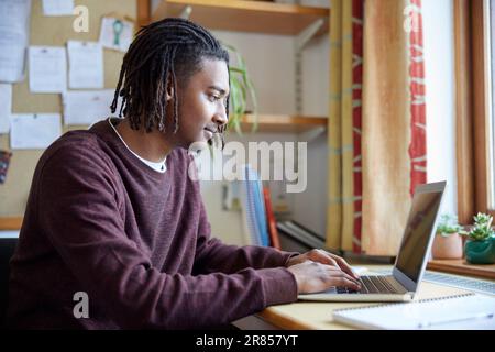 Male University Or College Student Studying With Laptop At Desk In Room Stock Photo