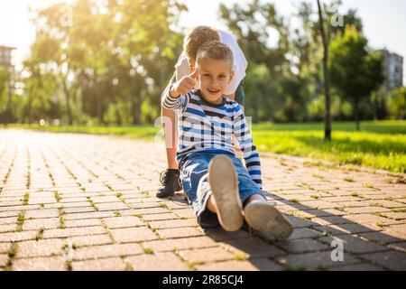 Two boys are having fun with skateboard in park. Playful children in park, happy childhood. Stock Photo