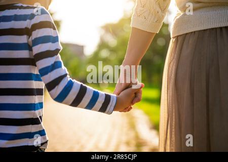 Close up of mother and son holding hands on sunny day. Stock Photo