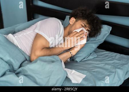 Cold and flu concept. Sick man suffering from running stuffy nose. Upset ill guy blowing her nose using paper napkin tissue. Stock Photo