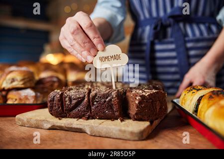 Sales Assistant In Bakery Putting Homemade Label Into Freshly Baked Baked Chocolate Brownies Stock Photo