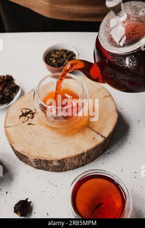 Different types of tea. Black, green and hibiscus sorts on a white table with teapot and glasses. Stock Photo