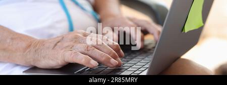Hands of elderly woman typing on laptop keyboard closeup Stock Photo
