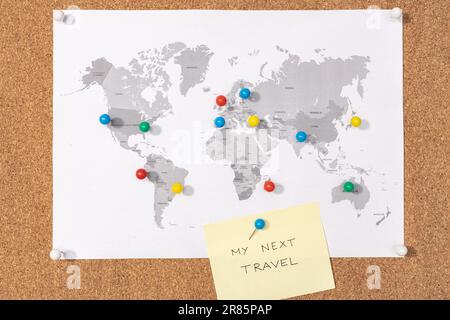 My next travel destination concept. Pushpins on world map on Corkboard and yellow sticky note Stock Photo