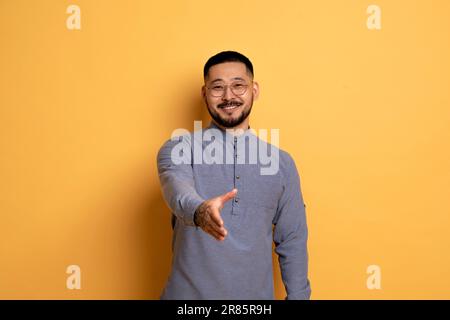 Smiling Young Asian Man Extending Hand For Handshake At Camera Stock Photo