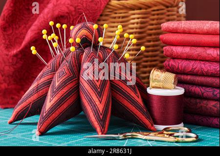 Set of red fabric and sewing tools on a craft mat, close-up view Stock Photo