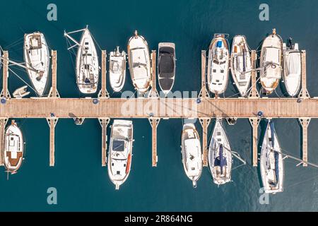 Yachts, sailboats and motorboats in a marina in Spain. On turquoise blue water of the Mediteranian sea. Aerial view seen from above. Stock Photo