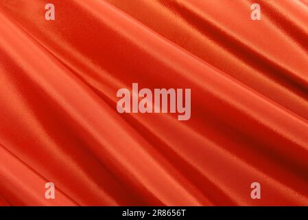 Texture of a smooth luxurious, elegant fabric in orange, red. Purple satin or silk fabric with folds and waves Stock Photo