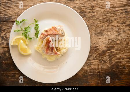 The home cooked cheek from an Anglerfish, Lophius piscatorius, that has been wrapped in bacon and fried. Served on mash. Anglerfish are sometimes call Stock Photo