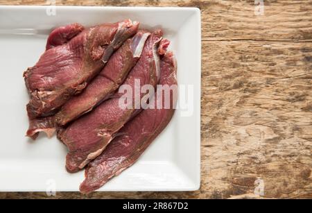 Raw venison slices from a wild roe deer, Capreolus capreolus, that are being prepared to be homecooked in a black bean sauce. England UK GB Stock Photo