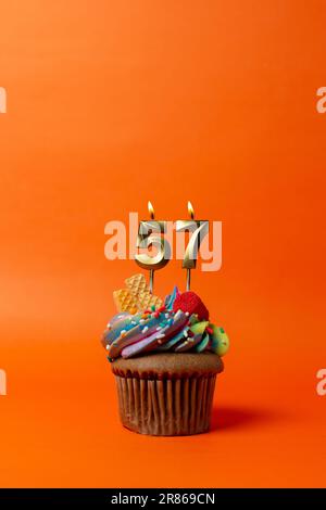 birthday cake with number 57 - cupcake on orange background with birthday candles Stock Photo