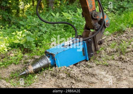 Log splitter mounted on a compact digger, High Bickington, North Devon, England, United Kingdom Stock Photo