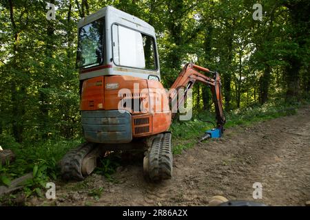 Log splitter mounted on a compact digger, High Bickington, North Devon, England, United Kingdom Stock Photo