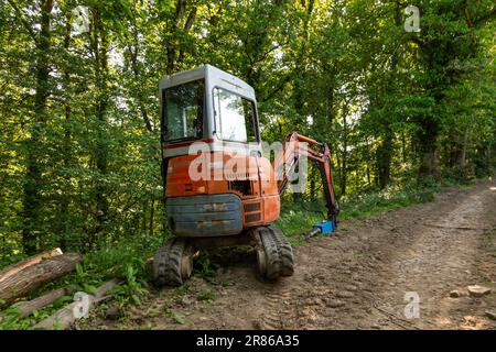 Log splitter mounted on a compact digger, High Bickington, North Devon, England, United Kingdom Stock Photo