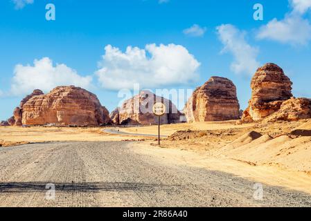 Desert road with slow sign and erosion canyon formations near Al Ula, Saudi Arabia Stock Photo